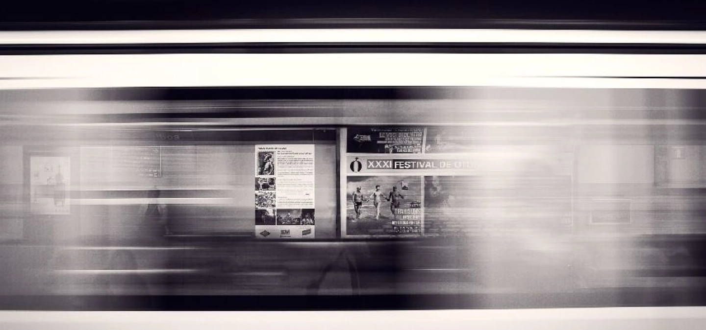 Photo en noir et blanc d'une station de métro et d'un métro en marche