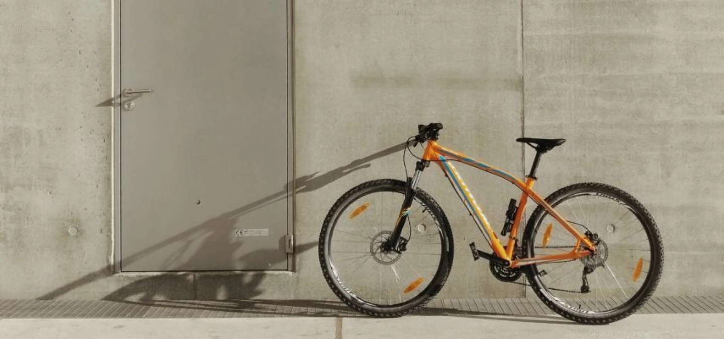 Photo d'un vélo jaune posé contre un mur de béton gris