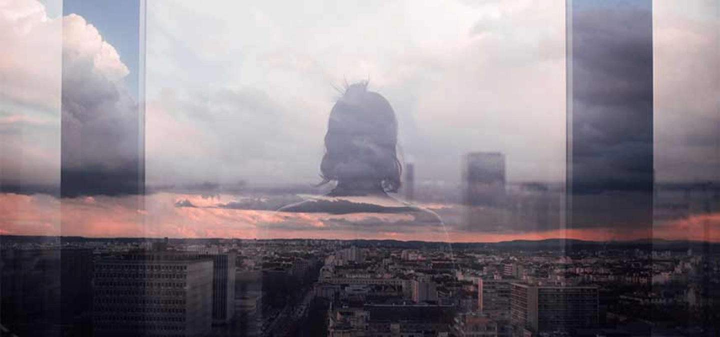 Reflet d'une personne dans une vitre donnant sur une vue de Lyon